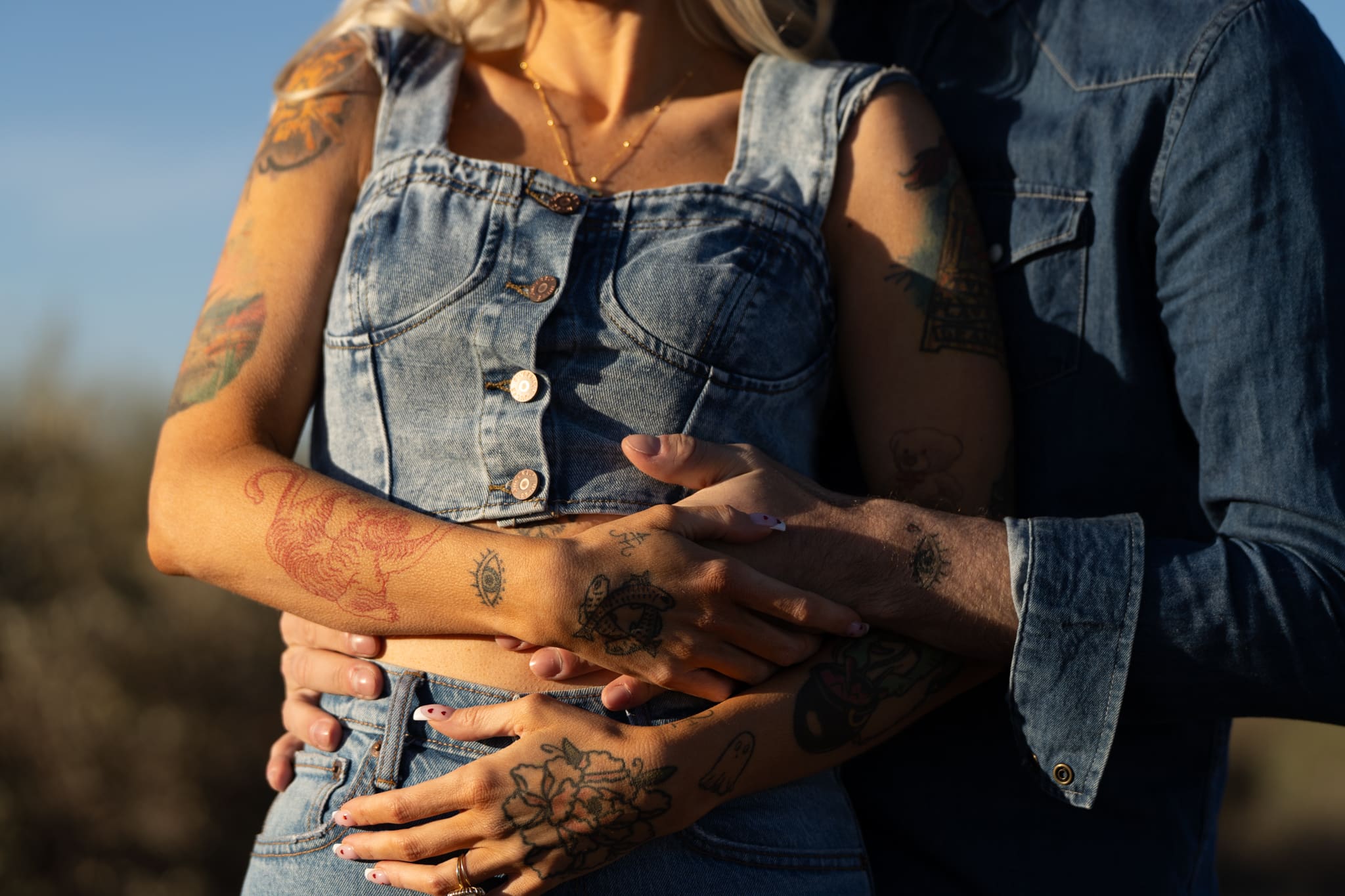 Tattooed couple in matching denim embracing during an intimate Iowa elopement in 2026
