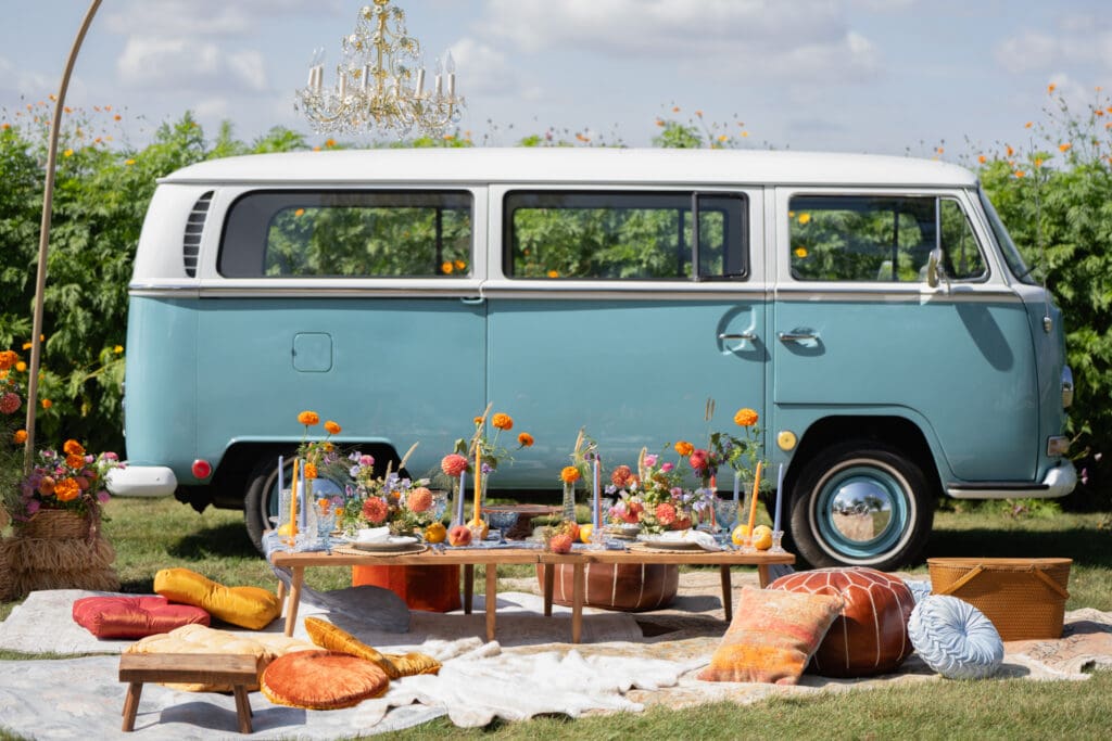 Retro blue bus surrounded by elegant floral arrangements and a styled tablescape for an intimate elopement boho picnic in Iowa
