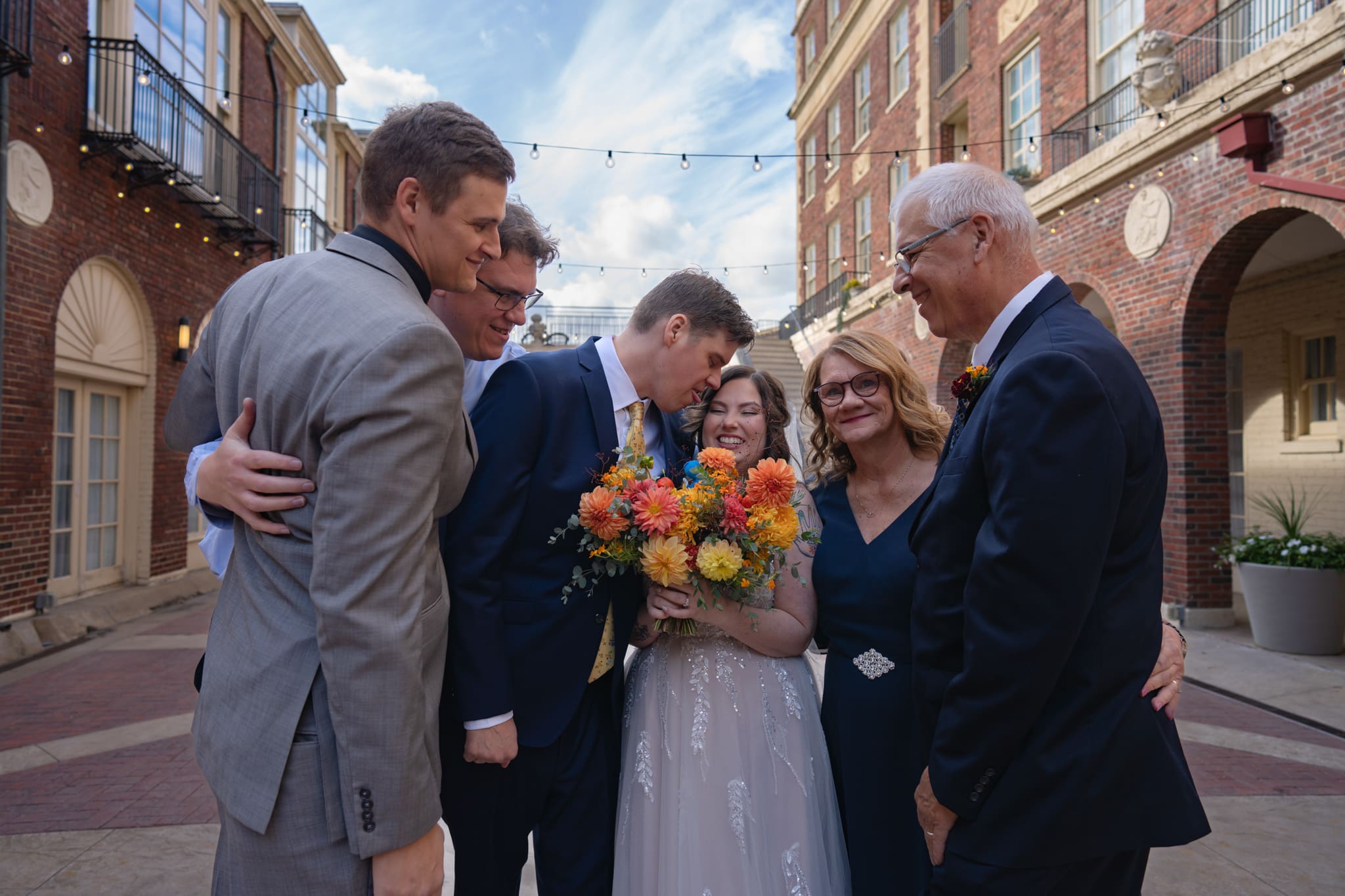 Bride and groom embraced by family in the courtyard of an elegant Iowa hotel wedding venue in 2026
