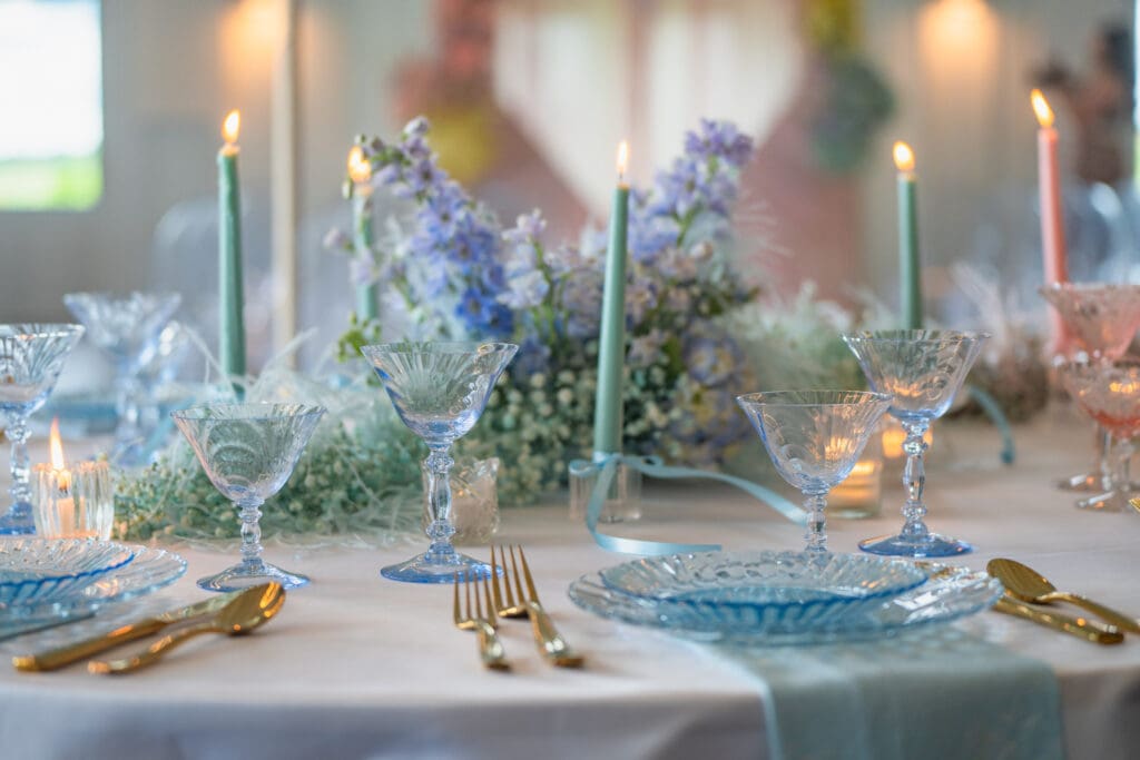 Elegant tablescape featuring vintage pastel blue glassware, floral arrangements, and styled wedding table decor